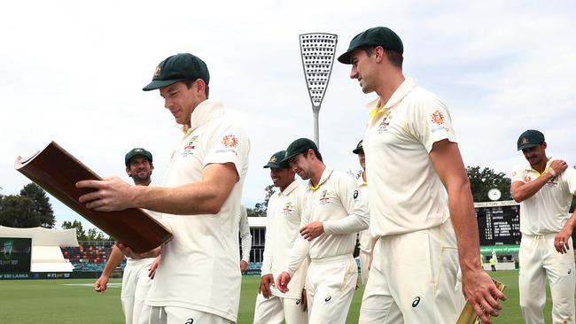 Australian captain Tim Paine looks at the series trophy with player of the series Pat Cummins at Manuka Oval. Picture: Phil Hillyard