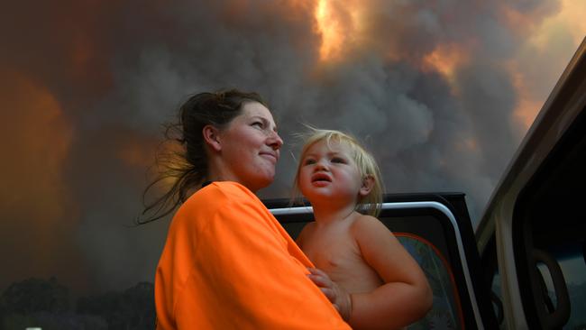 Sharnie Moren and daughter Charlotte look on as thick smoke rises above Nana Glen. Picture: AAP