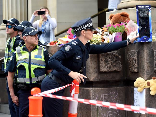 A police officer leaves a tribute. Picture: Nicole Garmston