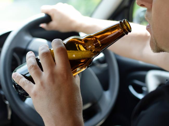 The concept of alcohol driving crime - closeup of young male driver hands with steering wheel and bottle of beer. Drink driving generic. Picture: iSTOCK