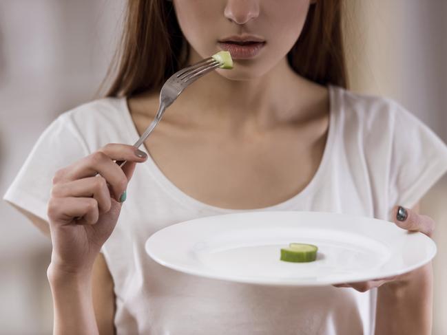 Thin girl with an empty plate standing in the center of the room closeup, malnutrition harms health. Picture: iStock