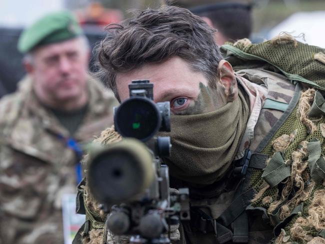 A British soldier looks into a telescopic sight as he holds his sniper rifle during the NATO DRAGON-24 military exercise in Korzeniewo, northern Poland.