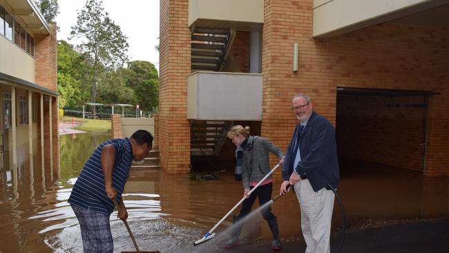 Trinity College principal Br John Hilet helps clean up the school after a flood.