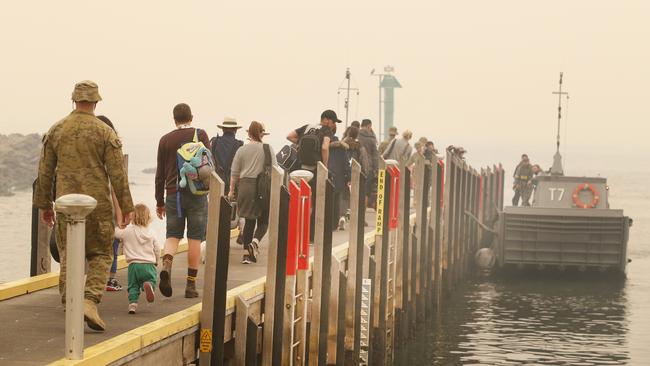 Evacuees walk out to board the landing boats to head out to the waiting ships. Picture: David Caird