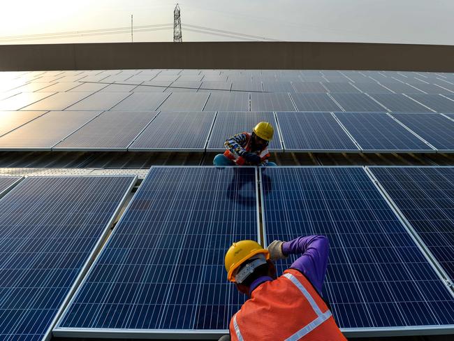 Indian labourers install solar panels at a site about 45km east of New Delhi. Picture: AFP