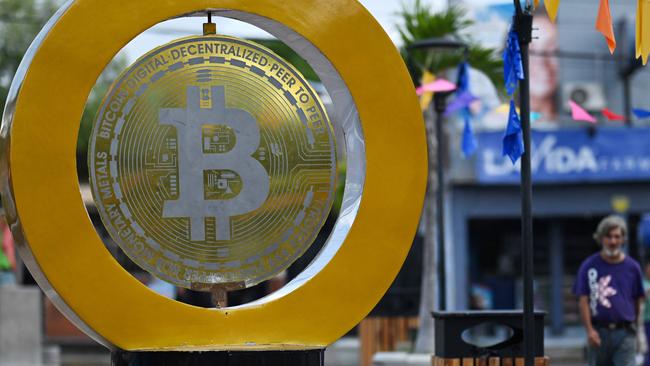 A man walks past a bitcoin monument at Plaza Bitcoin in San Salvador on September 4, 2024. According to the Institute for Public Opinion (IUDOP), Bitcoin adoption remains limited in El Salvador despite entering its third year as a legal currency. The NGO "My First Bitcoin" aims to promote cryptocurrency use by teaching it in public schools, with over 35,000 students attending their classes so far. While 88 out of 100 people reported not using Bitcoin in 2023, some, like taxi driver Napoleon Osorio, have embraced it in their businesses. "I started on my own" three years ago "and now manage 21 drivers," Osorio says. (Photo by Marvin RECINOS / AFP)