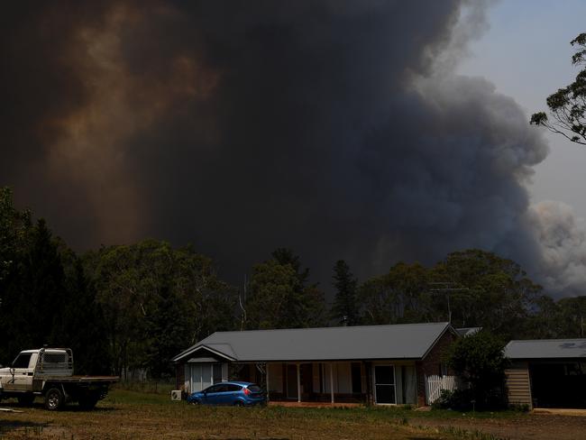 A home is seen as smoke from the Grose Valley Fire rises in the distance, at Bilpin. Picture: Dan Himbrechts