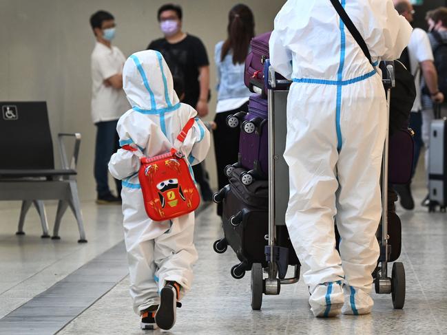 TOPSHOT - International travellers wearing personal protective equipment (PPE) arrive at Melbourne's Tullamarine Airport on November 29, 2021 as Australia records it's first cases of the Omicron variant of Covid-19. (Photo by William WEST / AFP)