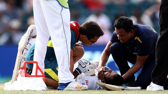 Dimuth Karunaratne of Sri Lanka receives medical attention after being struck by a Pat Cummins bouncer. Picture: Getty Images