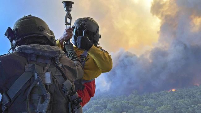 Rural Fire Service employee, Mr Allen Madden prepares to be winched down in the Lithgow area by Petty Officer Aircrewman Jason Wickman from an 808 Squadron MRH90 Taipan Military Support Helicopter over the Grose Valley bushfire in the Blue Mountains National Park. *** Local Caption *** The Australian Defence Force (ADF) is continuing to support Emergency Management Australia in firefighting efforts around the country.  Navy’s MRH-90 Taipan helicopters based at HMAS Albatross in Nowra have evacuated residents at risk on the New South Wales South Coast and continue with day and night time aerial fire mapping. An additional MRH-90 forward-deployed to western Sydney, has facilitated access by specialist RFS personnel to properties under threat from advancing fire in the Hartley Vale region. The helicopter was also tasked to support personnel evacuation and property assessment in the Blue Mountains – Lithgow region. ADF liaison officers are working side by side with emergency services personnel in the State Disaster Coordination Centre (SDCC) and within the New South Wales Rural Fire Service Headquarters.  Defence is also providing transport and other capabilities such as aviation ground support, logistics, engineering and accommodation to support the firefighting effort.