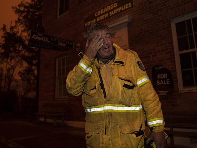 An exhausted Mr Allen on the main street of Cobargo just after the fire had swept through. Picture: Gary Ramage