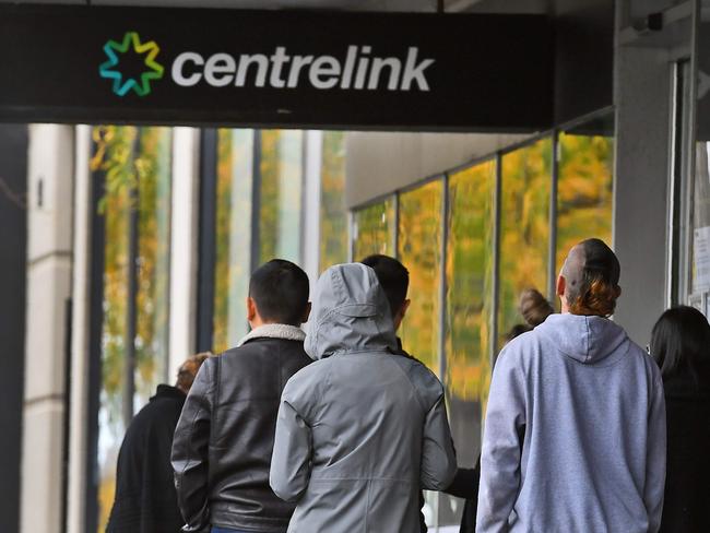 People queue up outside a Centrelink office in Melbourne on April 20, 2020, which delivers a range of government payments and services for retirees, the unemployed, families, carers and parents amongst others. - A report from the Grattan Institute predicts between 14 and 26 per cent of Australian workers could be out of work as a direct result of the coronavirus shutdown, and the crisis will have an enduring impact on jobs and the economy for years to come. (Photo by William WEST / AFP)