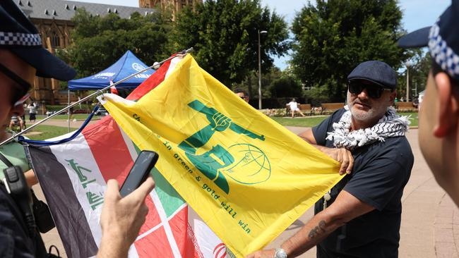 Al Yazbek holding a yellow flag that looks like the Hezbollah flag but has Ned Kelly on it at the protest in Hyde Park while talking to police. Picture: NewsWire / Damian Shaw Al Yazbek