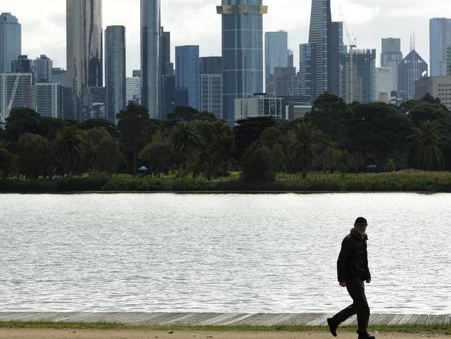 MELBOURNE, AUSTRALIA - NewsWire Photos June 02, 2022: A man walks around Albert Park Lake with the Melbourne skyline in the background on a day when the city temperature is not expected to go above 12'. Picture: NCA NewsWire / Andrew Henshaw