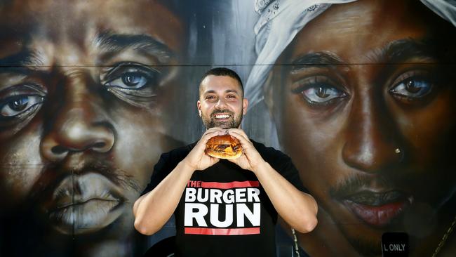 Aziz Ishak with a burger and the Mural of Rappers Biggie Smalls and Tupac Shakur on his Burger Run truck. The Burger Run mobile burger truck, with it's distinctive rap inspired artwork, is coming to Parramatta. Picture: John Appleyard
