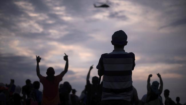 Migrants watch as a Mexican Federal Police helicopter flies over the border bridge connecting Guatemala and Mexico. Picture: Billy Santiago/AP