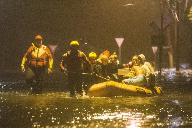 Narrabeen locals are evacuated by Surf Rescue from their homes as flood waters rise. Picture: Damian Shaw