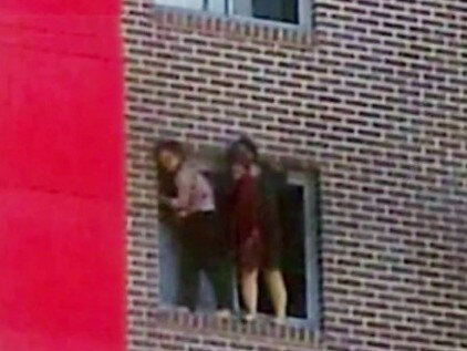 Pingkang Zhang and Yinuo Jiang cling to the windowsill of the burning apartment complex. Picture: ABC News