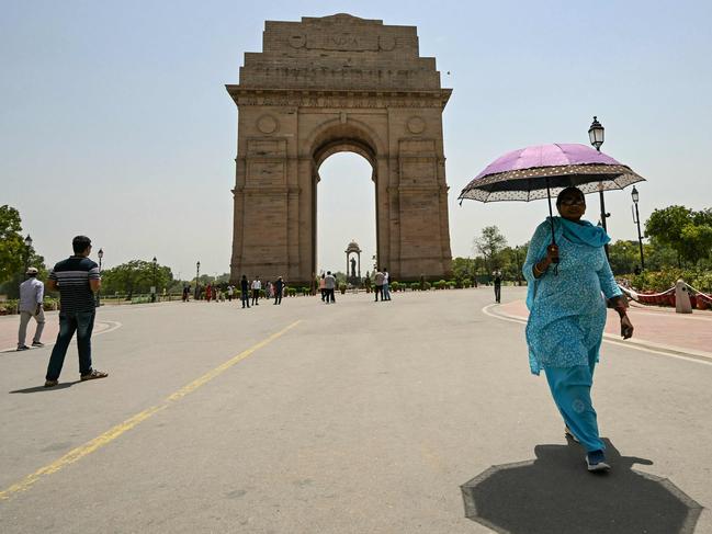 TOPSHOT - A woman holding an umbrella walks near the India Gate during severe heatwave on a hot summer day in New Delhi on May 29, 2024. Temperatures in India's capital have soared to a record-high 49.9 degrees Celsius (121.8 Fahrenheit) as authorities warn of water shortages in the sprawling mega-city. (Photo by Money SHARMA / AFP)