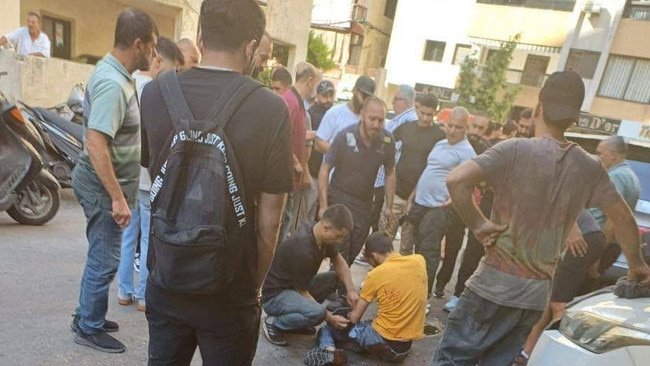 A crowd surrounds a Lebanese man on a busy street after he was injured by one of the remote-controlled exploding pagers.