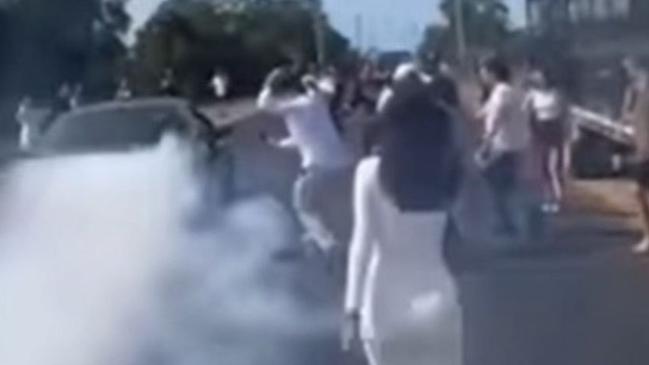 Some of the crowd outside watching as burnouts are done after the funeral