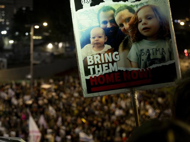 TEL AVIV, ISRAEL - DECEMBER 28: A protester holds a sign with photos of the Bibas family who is held hostage in the Gaza Strip during a rally calling for an hostages deal with Hamas on December 28, 2024 in Tel Aviv, Israel. Former hostages, family members of hostages, and thousands of their supporters are rallying for a deal to be made with Hamas to return the 100 people who remain captive in Gaza. The Israeli government and Hamas have blamed each other for stalled negotiations, after talks appeared to build momentum in recent weeks. (Photo by Amir Levy/Getty Images)