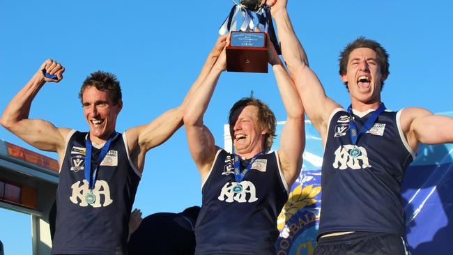 Kerang co-coaches Troy Coates and Travis Matheson flank captain Ryan Gillingham with the 2015 premiership cup.