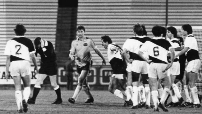 FIFA referee Don Campbell, second from left, clutches his head in pain after being struck from behind by an unknown player from Italian first division team Udinese in the international against Australia at Football Park in 1985.