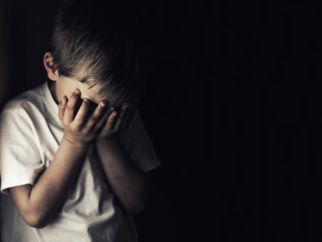 Depressed 6 years old child crying. Dark background.