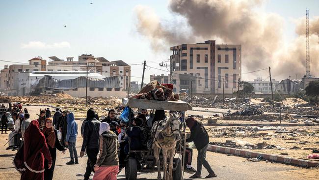 Smoke from bombardment billows in the background as civilians flee from Khan Younis. Picture: AFP