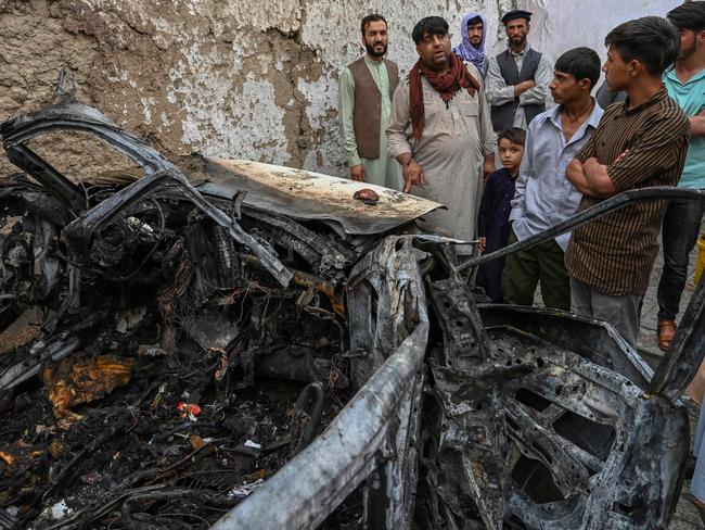 Afghan residents and family members of the victims gather next to a damaged vehicle inside a house, day after a US drone air strike in Kabul on August 30. Picture: AFP