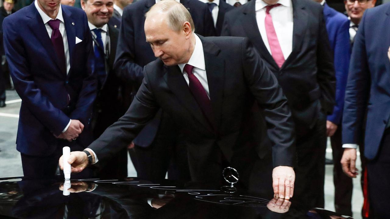 President Vladimir Putin signs the bonnet of a Mercedes during the opening ceremony of the Mercedes Benz car assembly plant outside Moscow – the company has now pulled out of Russia. Picture: Pavel Golovkin