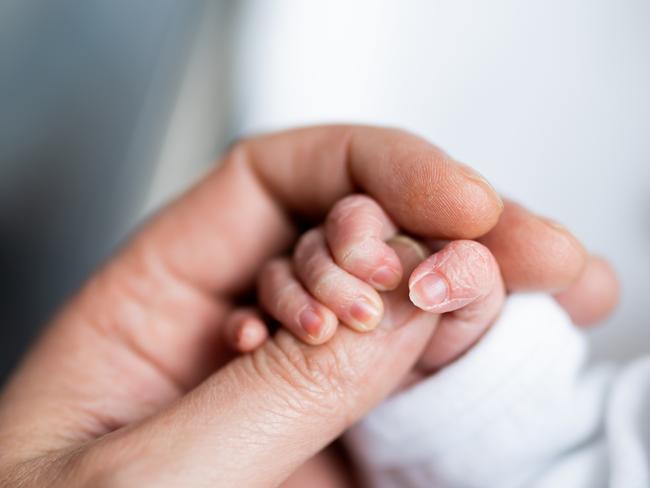 Hand of newborn baby who has just been born holding the finger of his father's hand.CREDIT ISTOCK