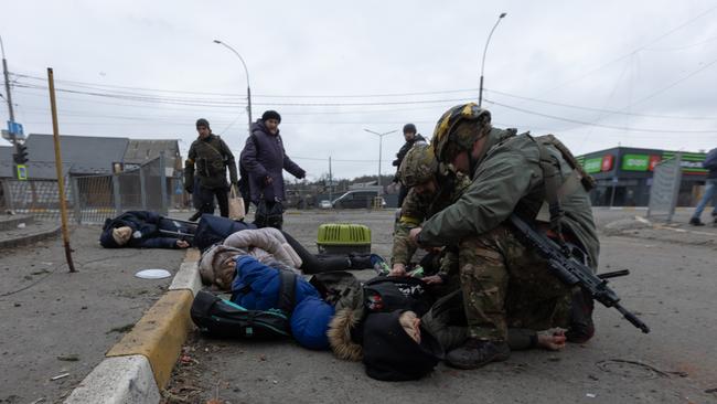 Ukrainian soldiers try to aid the victims of a mortar attack by Russian forces on Irpin on Sunday. Picture: Getty Images