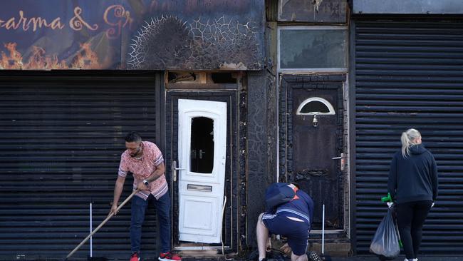 Restaurant owner Luqman Khan clears debris from the street in front of his restaurant in Middlesbrough, north east England following rioting and looting. Picture: AFP