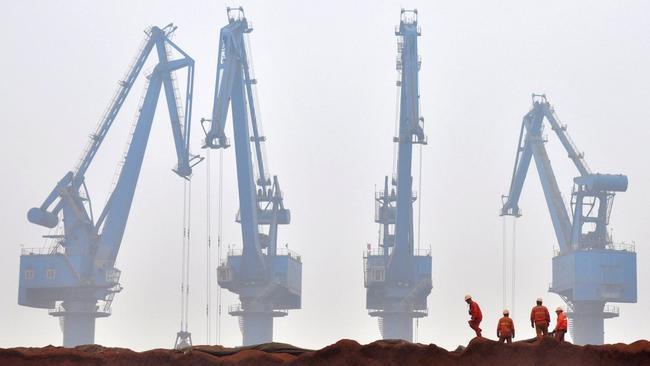 Workers prepare ore from Australia to be transported from a port in Tianjin. Picture: Reuters