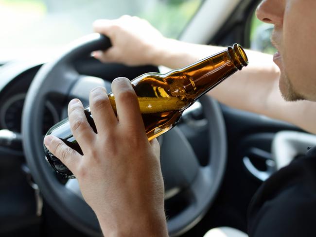 The concept of alcohol driving crime - closeup of young male driver hands with steering wheel and bottle of beer. Drink driving generic. Picture: iSTOCK