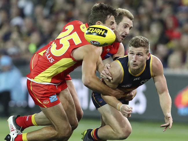 28/04/18 - AFL - Round 6 - Adelaide Crows v Gold Coast Suns at the Adelaide Oval. Rory Laird gets his handpass out from Jarryd Lyons and Michael Barlow. Picture SARAH REED