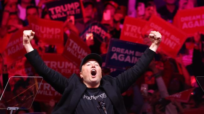 Tesla and X CEO Elon Musk raises his hands as he takes the stage during a campaign rally for Trump on October 27.