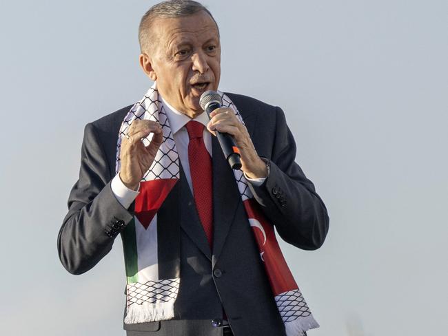 Turkish President Recep Tayyip Erdogan wears a scarf with both Turkish and Palestinian flags as he addresses a rally organised by the AKP party in solidarity with the Palestinians in Gaza, in Istanbul on October 28, 2023. (Photo by YASIN AKGUL / AFP)