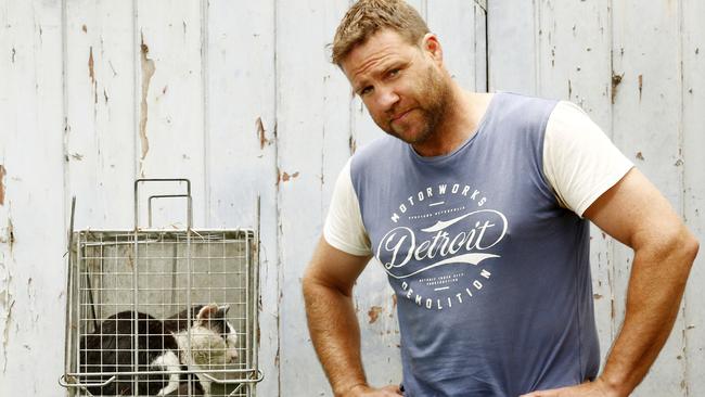 Christian Smits with the Feral cat he caught in his back yard. Picture: John Appleyard