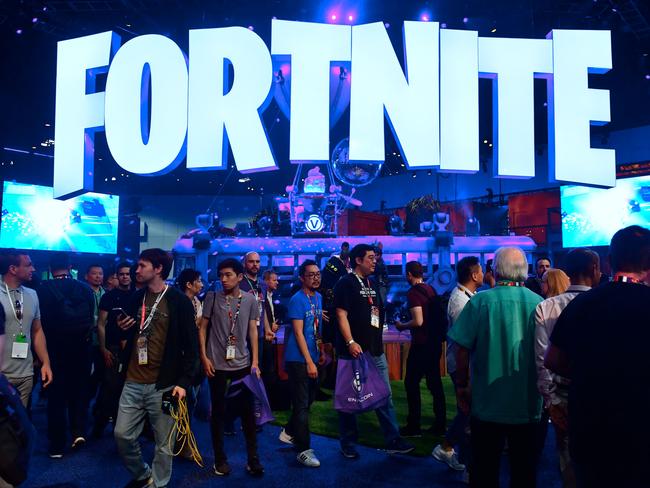 (FILES) This file photo taken on June 12, 2018 shows people crowding the display area for the survival game Fortnite at the 24th Electronic Expo, or E3 2018, in Los Angeles, where hardware manufacturers, software developers and the video game industry present their new games. - Fortnite's popularity took off last year after the release of a free "battle royale" version that lets up to 100 players vie to be the last character standing on ever-shrinking terrain. Dropped onto the battlefield with nothing, players have to scrounge for weapons as the fight for survival begins. (Photo by Frederic J. BROWN / AFP)