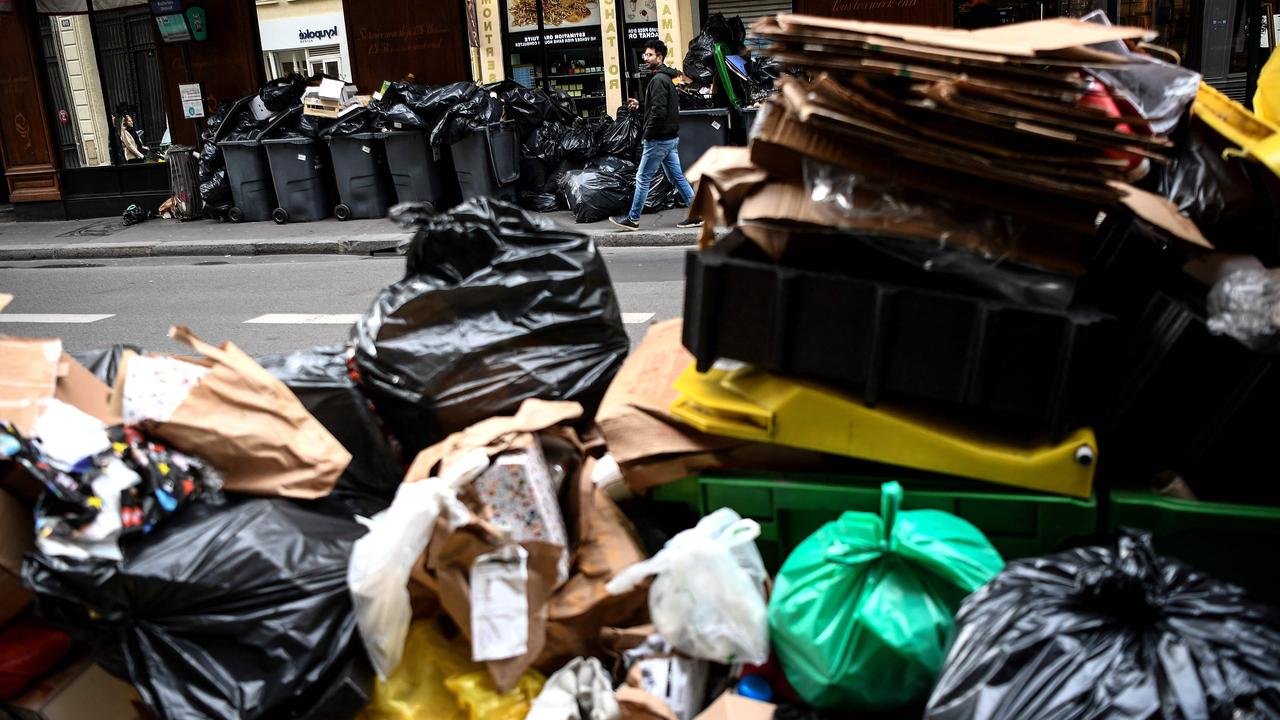 A man walks past a pile of garbage bags that have been piling up in Paris since waste collectors went on strike against the government’s proposed pensions reform. Picture: Christophe Archambault/AFP