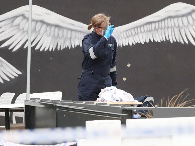 Bullet holes are visible in the wall behind a forensic officer. Picture: David Crosling