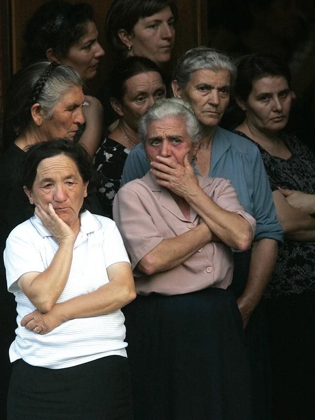 Women wait for the caskets of Francesco Giorgi, Sebastiano Strangio and Marco Marmo after their funerals following the mafia slaying that left six dead.