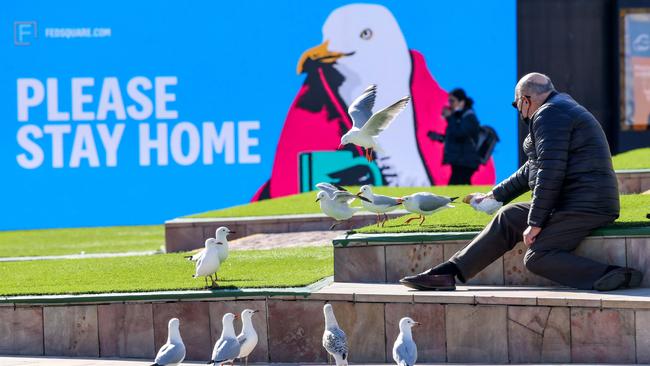 A man feeds birds in Federation Square in August last year during Melbourne’s second lockdown, which lasted 111 days. Picture: NCA NewsWire/Ian Currie