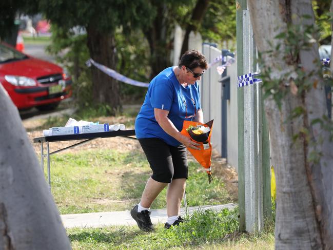 A mourner brings tributes to lay at the home. Picture: Max Mason-Hubers