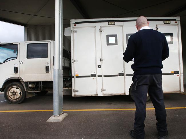Behind the walls of Port Phillip Prison. A prison guard stands beside a prison van at the admissions area.   Picture: David Caird