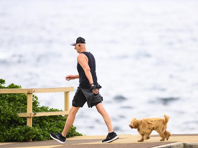 Man and dog walking.People at Eastern Beaches during Social Distancing due to the coronavirus crisis. Picture's Darren Leigh Roberts