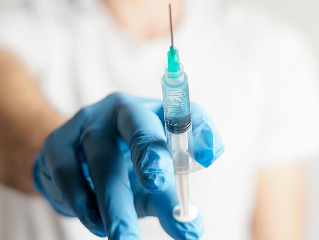 close-up of a vaccine dose in a syringe. doctor wears rubber gloves and holds the syringe. selective focus on the syringe. covid-19 corona virus vaccination.